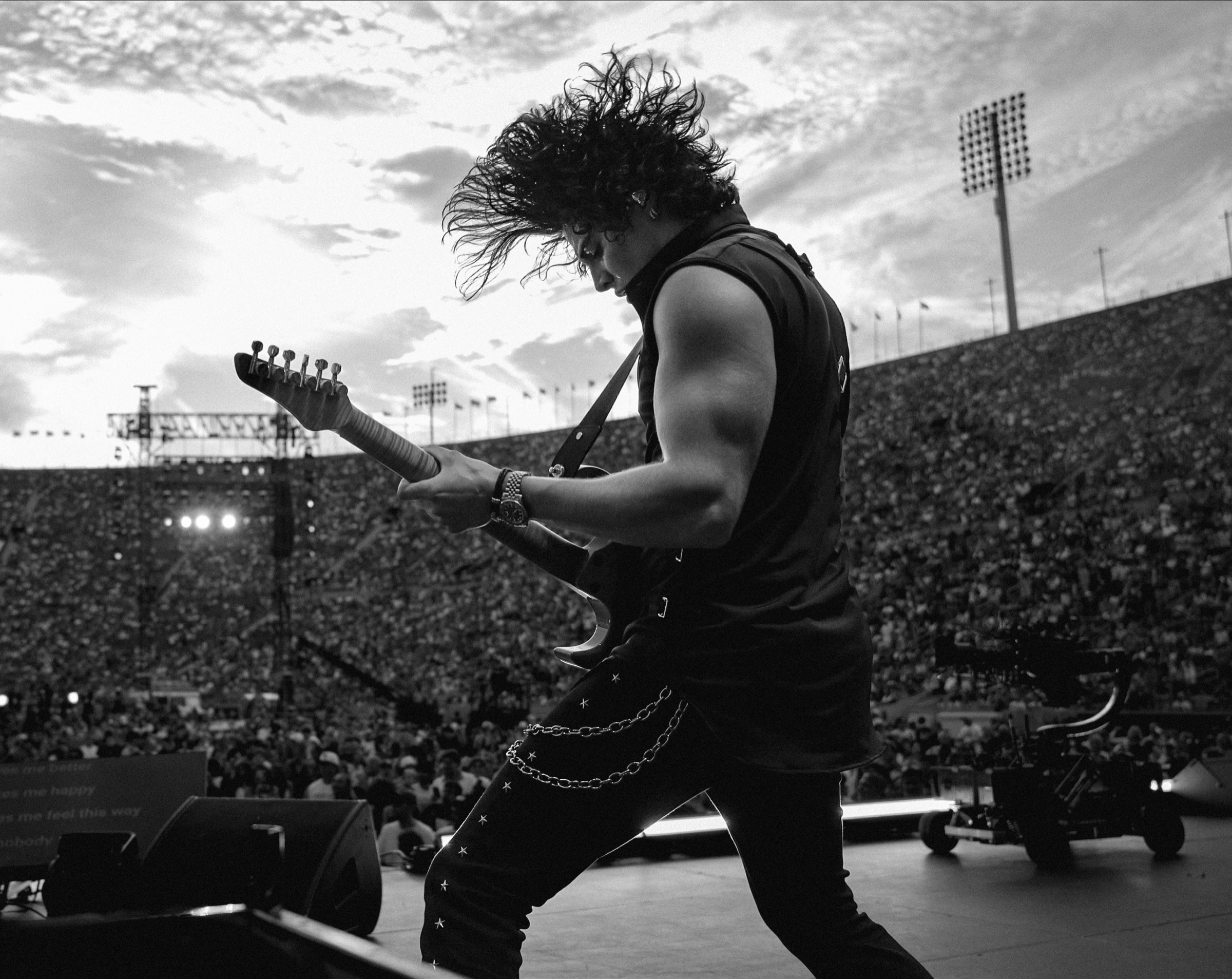 Jon Dretto performing guitar before a stadium audience at the Los Angeles Memorial Coliseum
